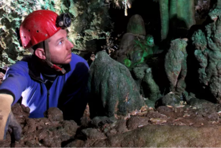 Géologue entouré de stalagtites et stalagmites vertes